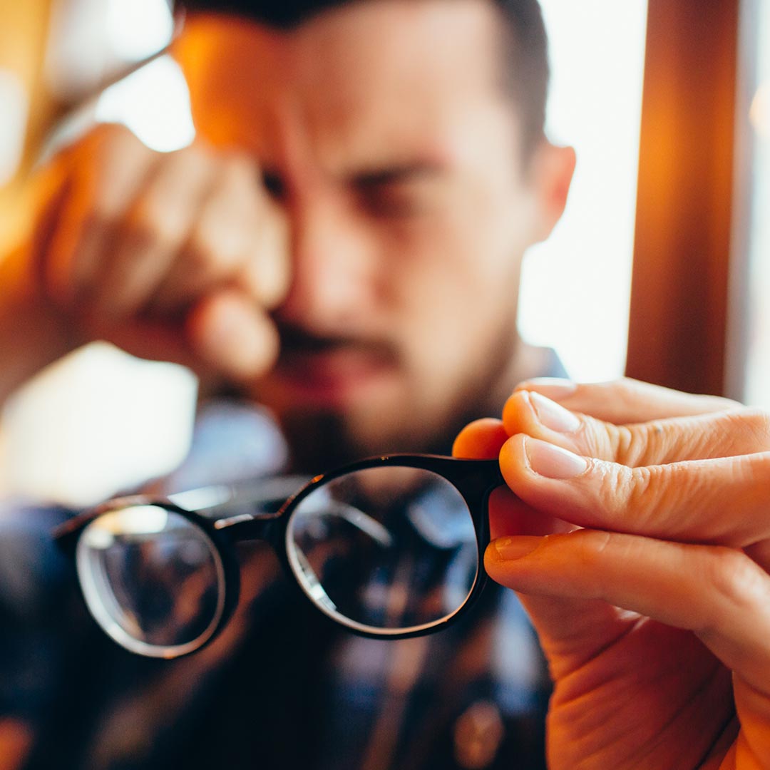 Man holding his glasses and rubbing his eye