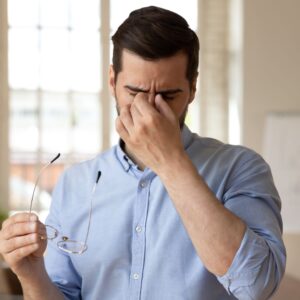 man rubbing his dry eyes