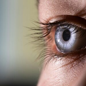 A macro close-up of a human eye highlighting the corneal surface and iris detail.