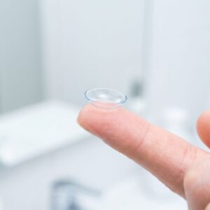 A detailed close-up of a clear contact lens resting on a fingertip