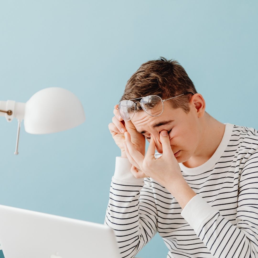a man rubbing eyes looking at laptop